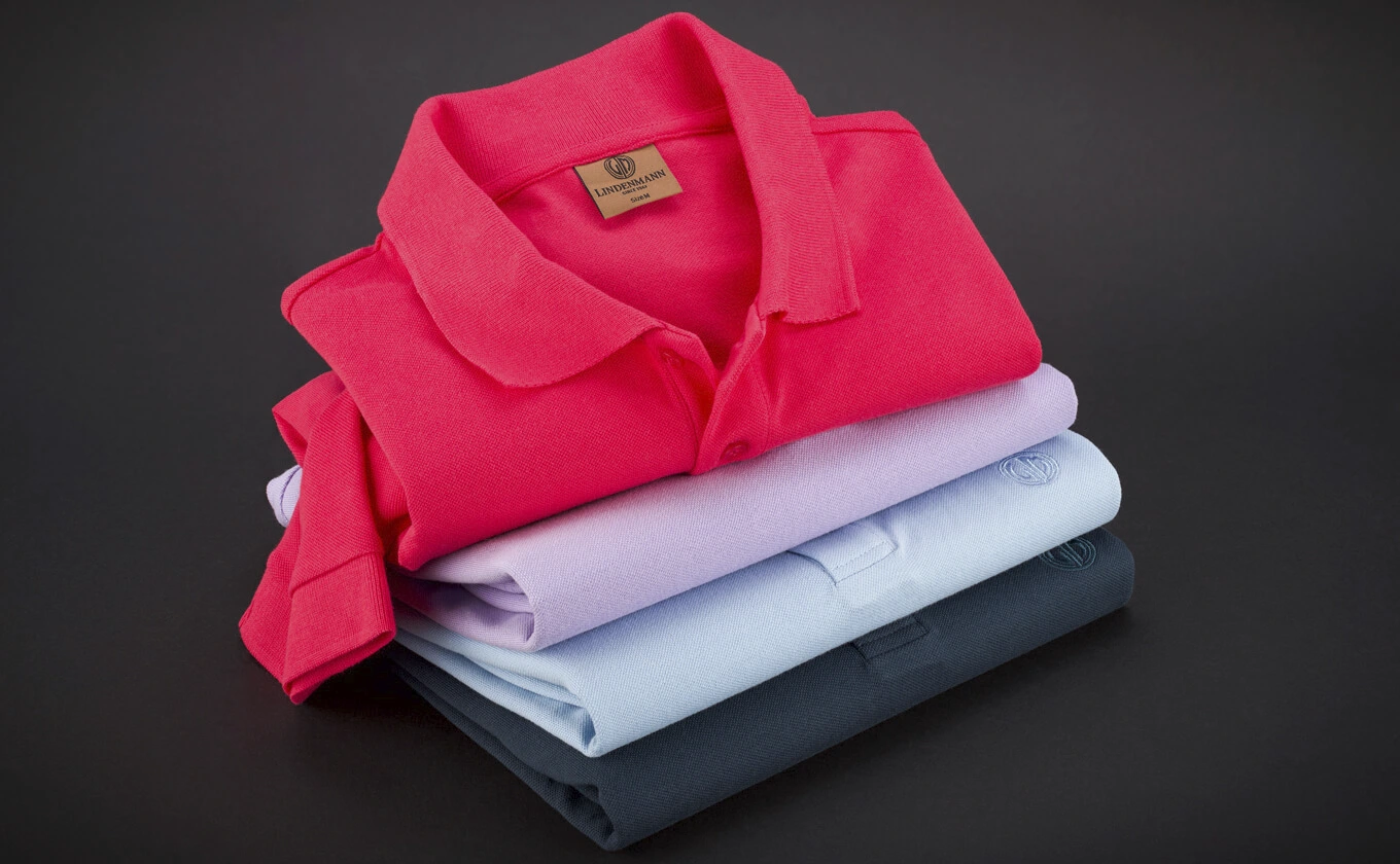 Gestapelte Polohemden in verschiedenen Farben, oben ein rotes Polohemd Gestapelte Polohemden in verschiedenen Farben, oben ein rotes Polohemd