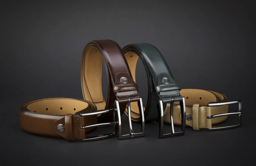 Vier Herren-Ledergürtel in verschiedenen Farben auf schwarzem Hintergrund Vier Herren-Ledergürtel in verschiedenen Farben auf schwarzem Hintergrund