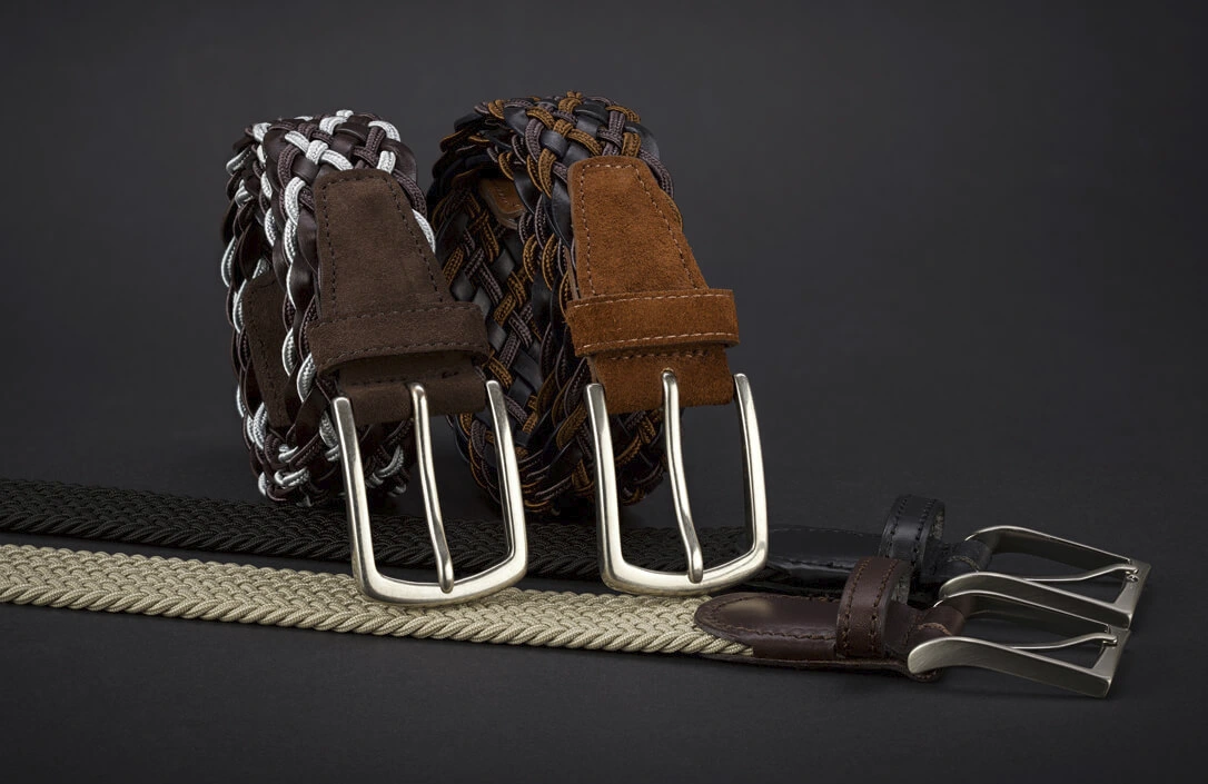 Vier geflochtene Herren-Gürtel in verschiedenen Farben auf schwarzem Hintergrund Vier geflochtene Herren-Gürtel in verschiedenen Farben auf schwarzem Hintergrund