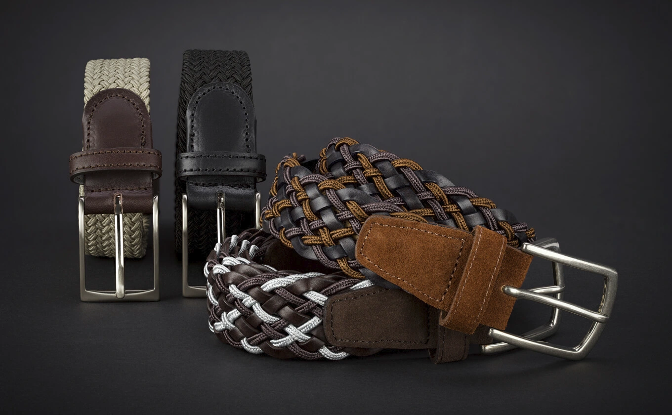 Vier geflochtene Herren-Gürtel in verschiedenen Farben auf schwarzem Hintergrund Vier geflochtene Herren-Gürtel in verschiedenen Farben auf schwarzem Hintergrund