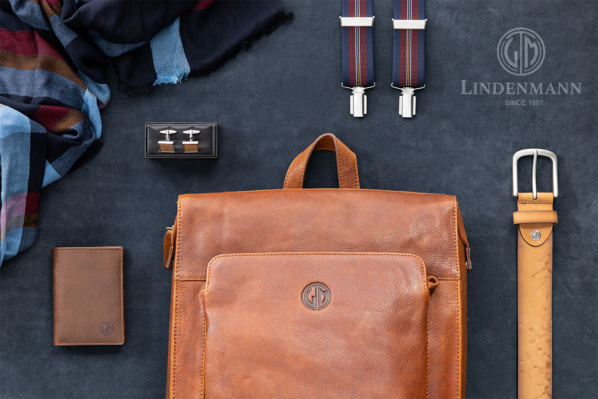 Lindenmann Accessoires auf blauem Hintergrund – Ledergürtel, Tasche, Geldbeutel, Hosenträger und Manschettenknöpfe